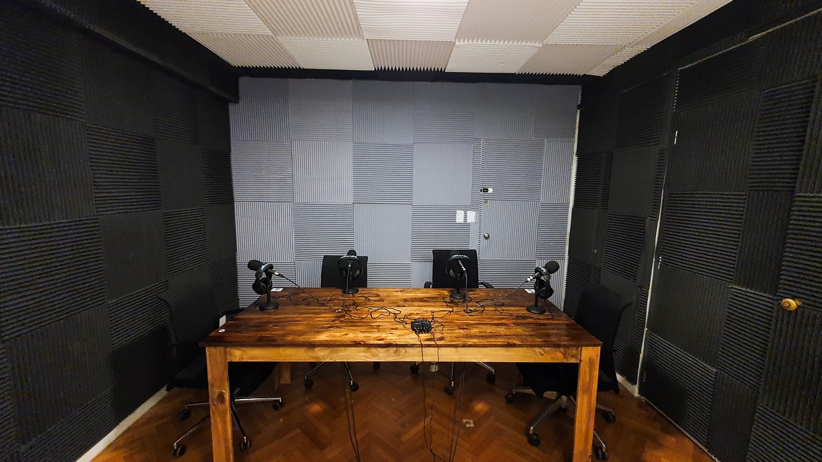 Sala de podcast del estudio DIGITV: paneles acusticos, mesa de madera y cuatro microfonos con auriculares